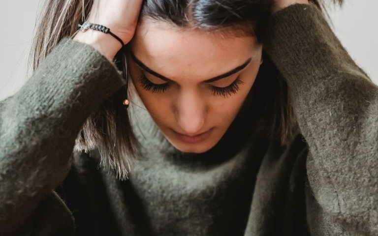 eine junge Frau rauft sich vor Verzweiflung die Haare