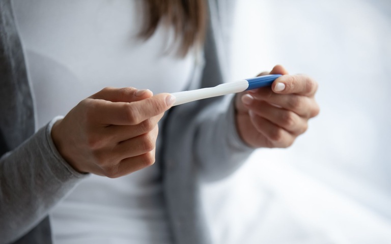 eine Frau hält einen Schwangerschaftstest in den Händen