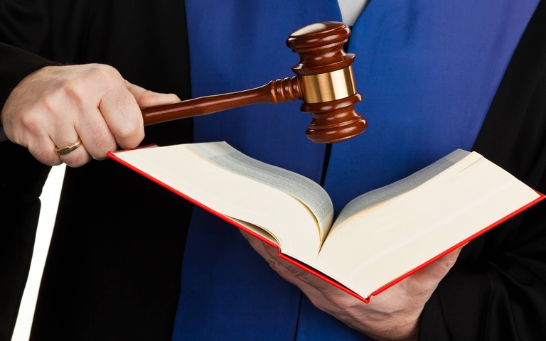 Ein Richter mit einem Gesetzbuch bei Gericht.