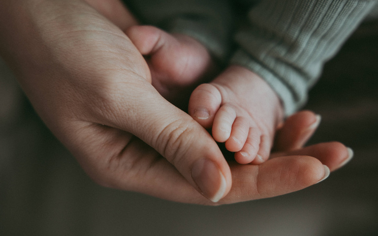 Nahaufnahme der Hand der Mutter, die die Beine des Babys hält