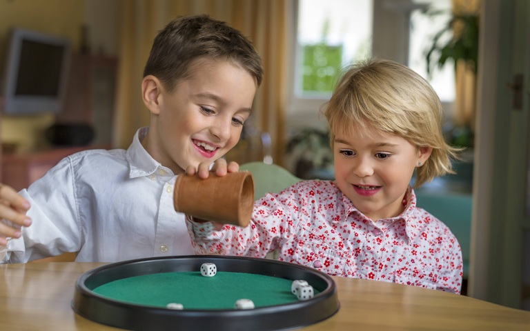 Bruder und Schwester spielen zusammen ein Würfelspiel 