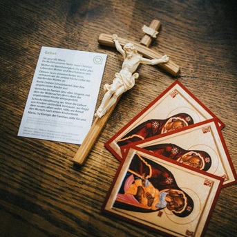 ein Holzkreuz mit Gebetskärtchen zur Mutter unseres Herrn