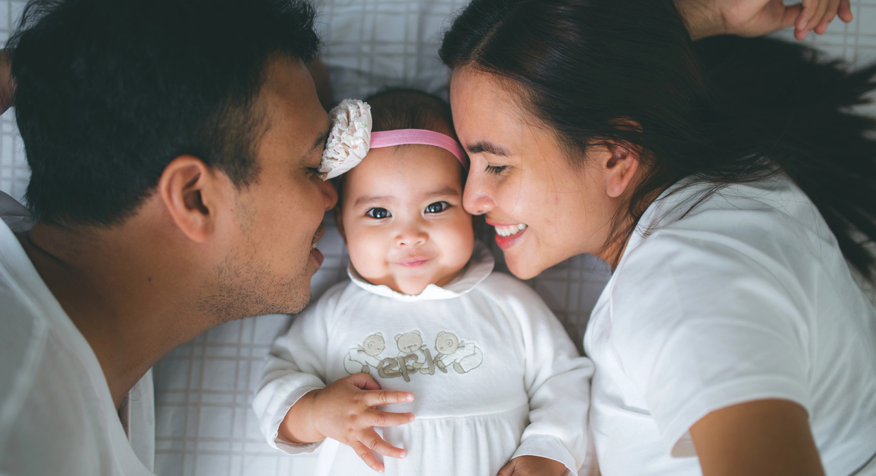 Parents kissing baby